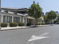 an arrow is pointing to an empty street next to buildings with green trees lining both sides