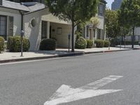 an arrow is pointing to an empty street next to buildings with green trees lining both sides