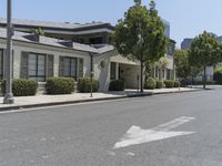 an arrow is pointing to an empty street next to buildings with green trees lining both sides