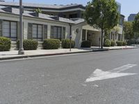 an arrow is pointing to an empty street next to buildings with green trees lining both sides