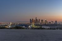 the view of los at twilight from the hills with city lights in the distance and a man taking a photo