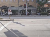 a person crossing the street near many tables at an intersection with several people sitting at tables