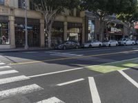 a traffic light in the middle of a street and cars parked on it with trees around