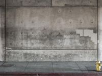 a red fire hydrant sits against a concrete wall and concrete ground in the city