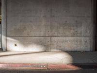 a red fire hydrant sits against a concrete wall and concrete ground in the city
