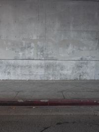 a red fire hydrant sits against a concrete wall and concrete ground in the city