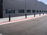 there is a gray building with red curbs and parking meters on the side of the road