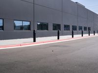 there is a gray building with red curbs and parking meters on the side of the road