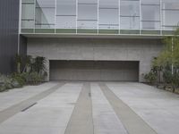 concrete courtyard with various potted plants outside an office building on gray stucco and white walls