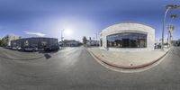 the view from a fisheye lens of a car dealership at an intersection with palm trees in the background