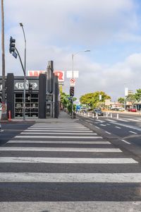 a person crossing the street with his motor cycle nearby and a shop building and palm trees in the background