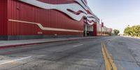 the red wall has the large sign above it on the side of the building and road