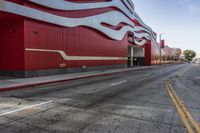 the red wall has the large sign above it on the side of the building and road