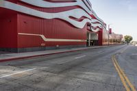 the red wall has the large sign above it on the side of the building and road