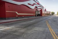 the red wall has the large sign above it on the side of the building and road