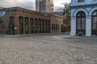 a brick sidewalk with a building and a blue car parked in the middle of it