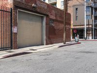 a building with a metal door sitting on a sidewalk next to a road in front of a metal gate