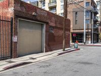 a building with a metal door sitting on a sidewalk next to a road in front of a metal gate