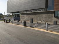 an asphalt street with a bike rack, parking meters and an open road with stairs