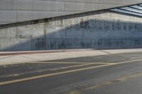 a man in a hat skates under an overpass on the side of a road