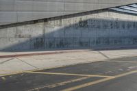 a man in a hat skates under an overpass on the side of a road