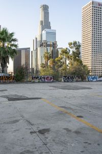 a concrete parking lot with lots of grafitti in the foreground and buildings in the background