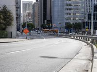 an empty roadway in the middle of a city area with buildings in the background and a pedestrian sign at the end