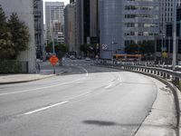 an empty roadway in the middle of a city area with buildings in the background and a pedestrian sign at the end