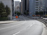 an empty roadway in the middle of a city area with buildings in the background and a pedestrian sign at the end