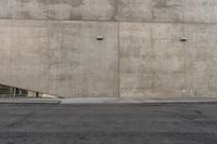 the corner of an industrial concrete wall has a large hole in it and several lights are on