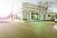 the building sits near a car on the road and trees on the street in front