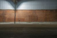 a red brick wall near a street at night with a lamp hanging on it's side