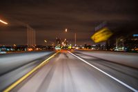 night shot with motion blurs on an interstate highway, and buildings in the background