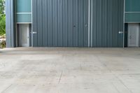 a fire hydrant sitting on a cement floor in front of a building with a steel facade