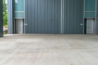 a fire hydrant sitting on a cement floor in front of a building with a steel facade