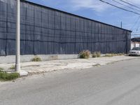 a car is driving down the street near an industrial building in california city with a privacy fence