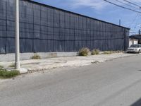 a car is driving down the street near an industrial building in california city with a privacy fence