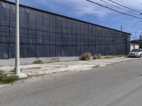 a car is driving down the street near an industrial building in california city with a privacy fence