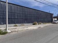 a car is driving down the street near an industrial building in california city with a privacy fence