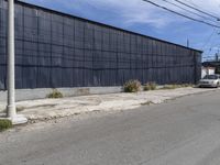 a car is driving down the street near an industrial building in california city with a privacy fence