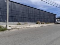 a car is driving down the street near an industrial building in california city with a privacy fence