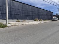 a car is driving down the street near an industrial building in california city with a privacy fence