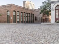 an empty brick patio with a fire hydrant near by some buildings and trees in the background