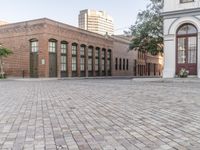 an empty brick patio with a fire hydrant near by some buildings and trees in the background