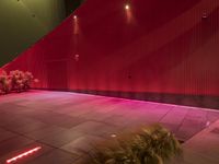 this is an indoor public space with a bench on the concrete floor and a planter with red lights above it