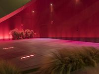 this is an indoor public space with a bench on the concrete floor and a planter with red lights above it