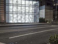 a building has a glass front in a city street, with greenery in front