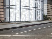 a building has a glass front in a city street, with greenery in front