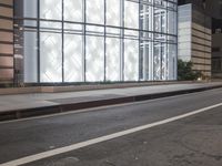 a building has a glass front in a city street, with greenery in front