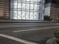 a building has a glass front in a city street, with greenery in front